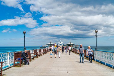 Llandudno, Walls - 05 Temmuz 2021 İnsanlar Llandudno Rıhtımı 'nda güneşli havanın tadını çıkarırlar. Galler 'in en uzun iskelesi Llandudno sahilinin muhteşem manzarası, rahatlatıcı bir gezinti ve eğlence sunar.