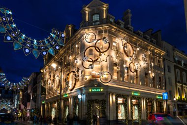 Londra, İngiltere - 30 Kasım 2025: Bu yıl Bond Caddesi Noel ışıkları, altın yıldız ve yüzüklerin sergilendiği Rolex mağazası ile parıltılı taç ve taç kemerlerinin sergilendiği bir yer.