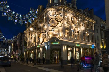 Londra, İngiltere - 30 Kasım 2025: Bu yıl Bond Caddesi Noel ışıkları, altın yıldız ve yüzüklerin sergilendiği Rolex mağazası ile parıltılı taç ve taç kemerlerinin sergilendiği bir yer.