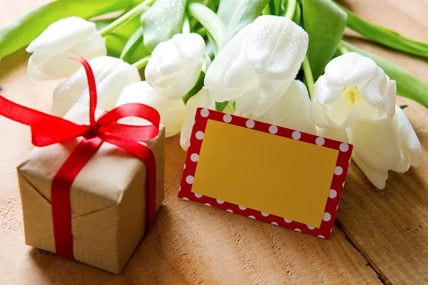 White tulip bouquet and gift box on wooden table . — Stock fotografie