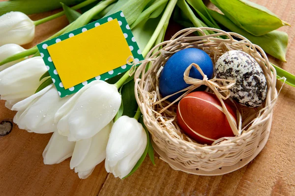 .Easter basket with colored eggs and white tulips. — Stock Photo, Image