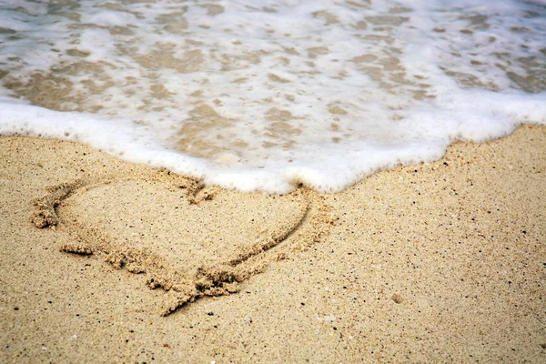 Heart symbol on the sand and sea wave. — Stock Photo, Image