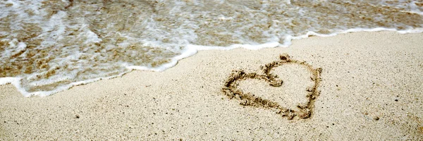 Heart symbol on the sand and sea wave. — Stock Photo, Image