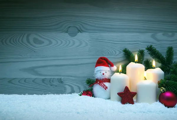 Čtyři hořící adventní svíčky a sněhulák s vánoční výzdobou. — Stock fotografie
