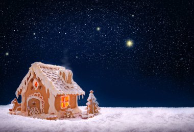 Gece gökyüzünde izole edilmiş beyaz kar üzerinde zencefilli kek evi.