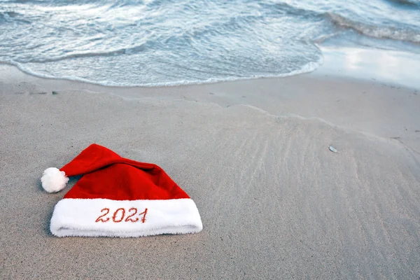 Anno 2021 scritto al cappello di Babbo Natale sulla spiaggia dei caraibi. — Foto Stock