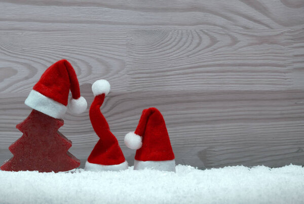 Шляпа Санта-Клауса и красная ель на снегу.