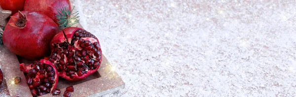 Romãs maduras frescas no fundo da neve e luzes de Natal. — Fotografia de Stock