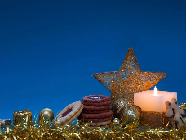 Advent candle with golden decoration and christmas cookies.