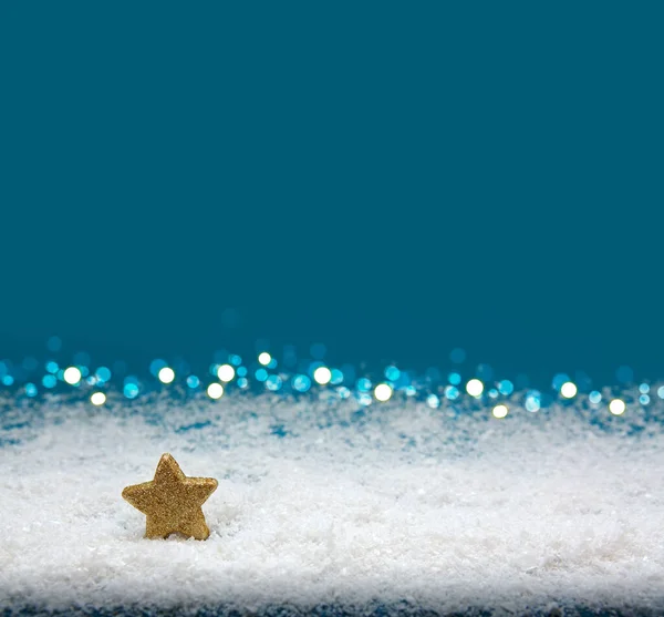 青い背景に孤立した白い雪の上の黄金の星. — ストック写真