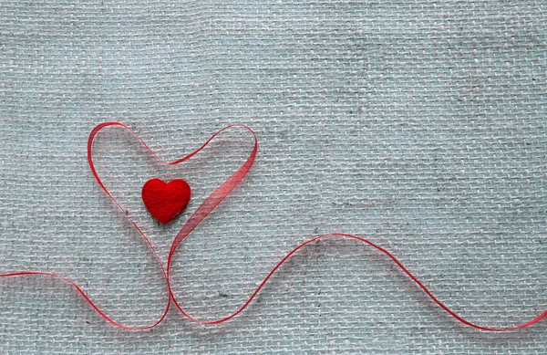 赤いハートリボンがグレーの布の背景に隔離されたバレンタインデーの背景. — ストック写真