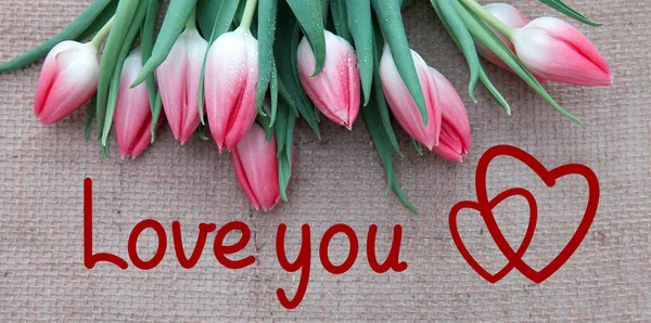 Pink tulips and two red hearts isolated on a cloth background. — Stock Photo, Image