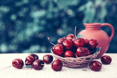 Sepette büyük kırmızı kirazlar ve yeşil üzerine izole edilmiş bir sürahi süt..