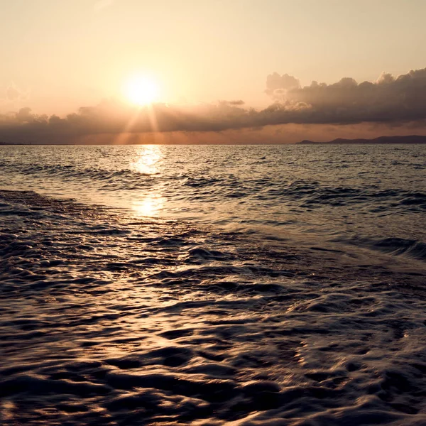 Um belo nascer do sol com uma onda e areia.Praia da Grécia. — Fotografia de Stock