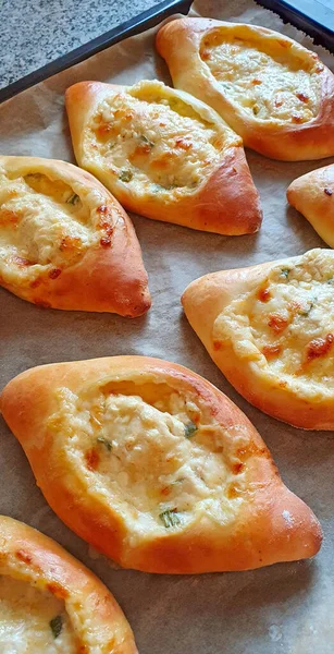 Baked khachapuri with cheese on baking paper. — Stock fotografie