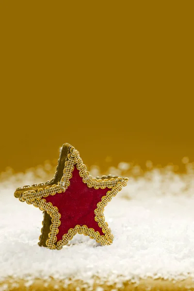 黄色の背景に隔離された白い雪の上の赤い星. — ストック写真