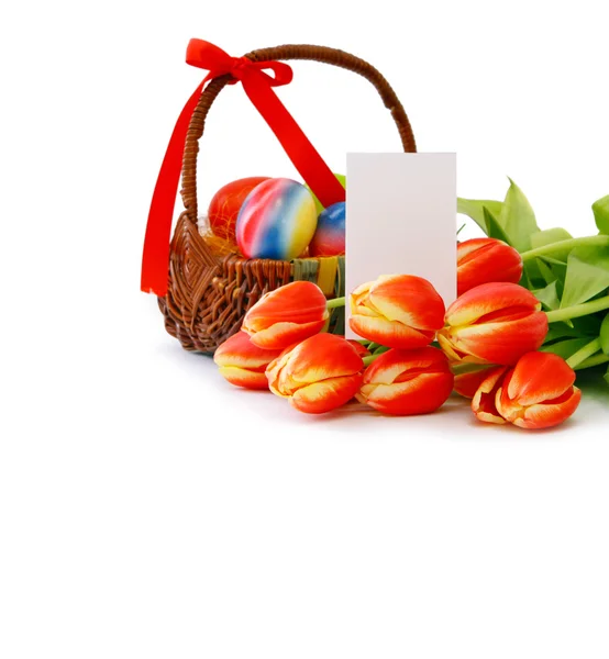 Colorful Easter eggs in a basket and red tulips. — Stock Photo, Image