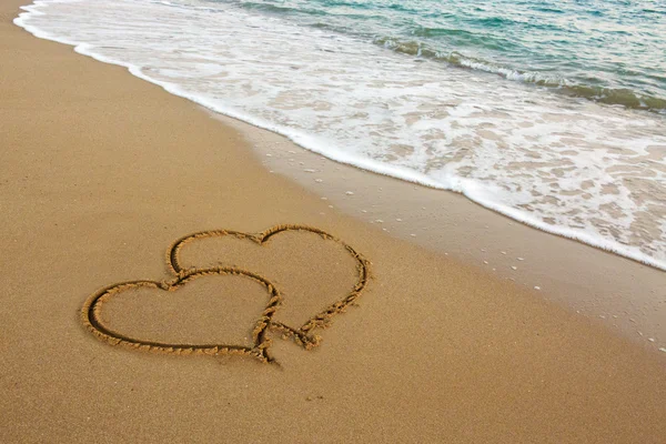 Twee liefde harten op zand. — Stockfoto