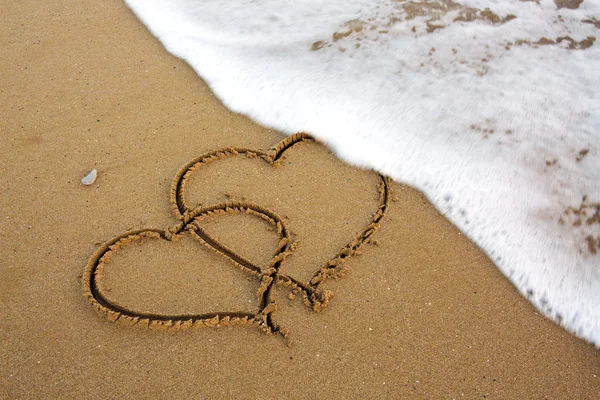 İki aşk kalbi kum üzerinde. — Stok fotoğraf