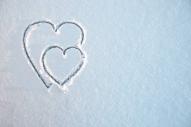 Kışın beyaz, taze bir karda iki kalp şekillenir. Yaklaş. Sevgililer Günü arkaplanı