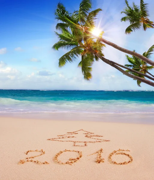 Año Nuevo 2016 escrito en la playa de arena y el sol . — Foto de Stock