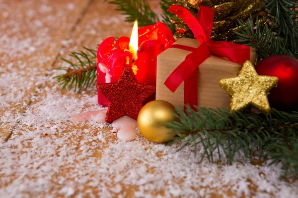 Vánoční dárek na dřevěném stole, vánoční stromek, červená svíčka . — Stock fotografie