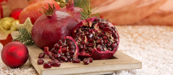 Frische reife Granatäpfel auf Holzgrund und Weihnachtsdekoration. — Stockfoto