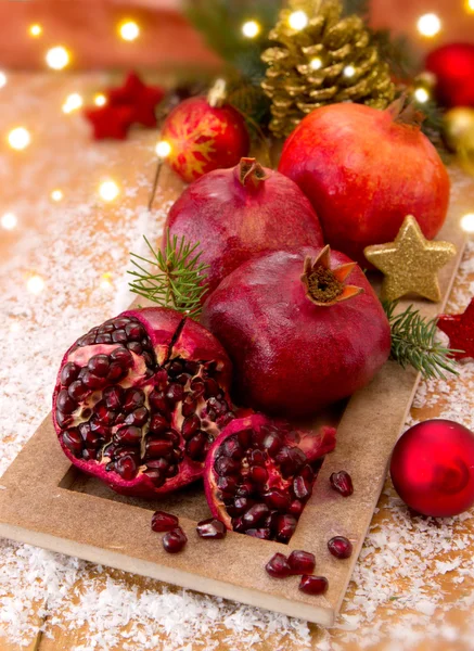 Frische reife Granatäpfel auf Holzgrund und Weihnachtsdekoration. — Stockfoto