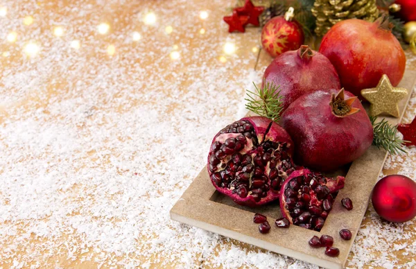 Frische reife Granatäpfel auf Holzgrund und Weihnachtsdekoration. — Stockfoto