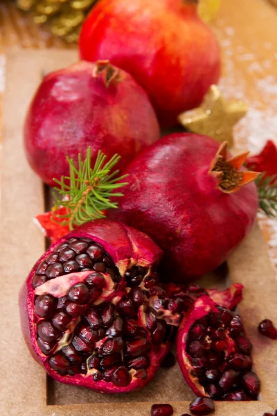 Frische reife Granatäpfel auf Holzgrund und Weihnachtsdekoration. — Stockfoto