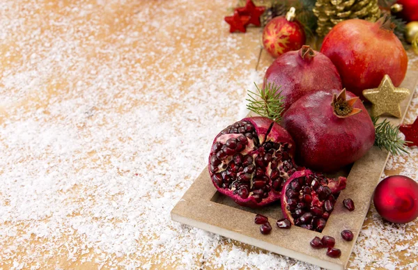 Frische reife Granatäpfel auf Holzgrund und Weihnachtsdekoration. — Stockfoto