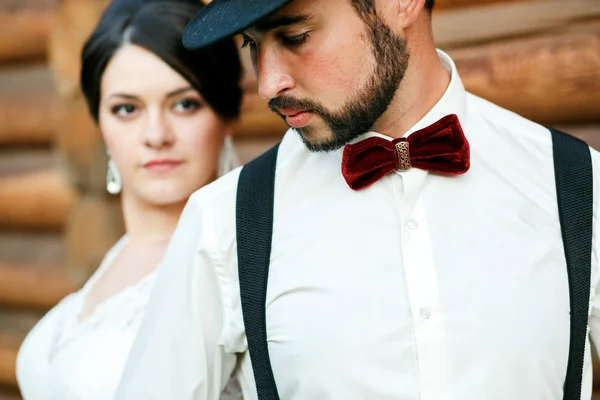 戴着帽子与胡须、 胡子、 领结和吊带的周到新郎。新娘穿着白色的婚纱礼服。黑帮风格. — 图库照片