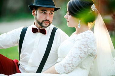 Şık gelin ve damat ışınları güneş ışığı ayarlama çim üzerinde durur. Yeni evli çift.