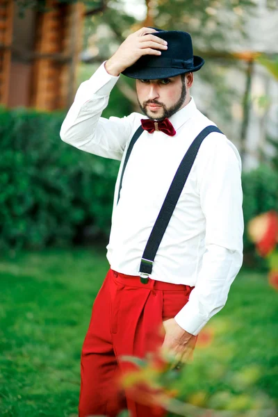 Macho homme dans un chapeau et pantalon rouge avec des bretelles . — Photo