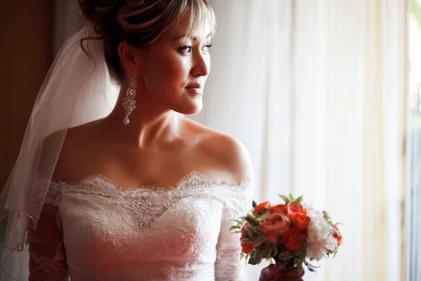 Menyasszony, esküvői csokor mellett ablak profil portréja. — Stock Fotó