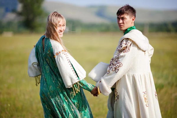 Couple en costumes ethniques tenir la main tourné en arrière à la caméra . — Photo