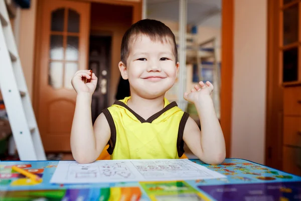 Маленький хлопчик щасливий сидить за столом після малювання, дошкільна домашня освіта . Ліцензійні Стокові Зображення