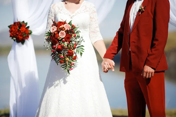 Hochzeit im Stil Marsala Farbe. Braut und Bräutigam halten Händchen am Altar. — Stockfoto