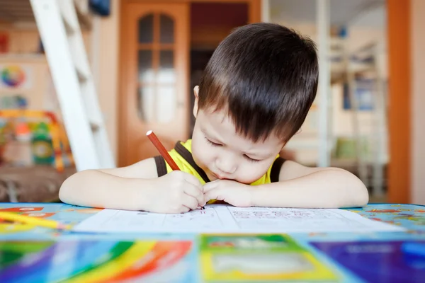 Drukke kleine jongen tekening met behulp van voelde pennen thuis met kleurrijke interieur. — Stockfoto