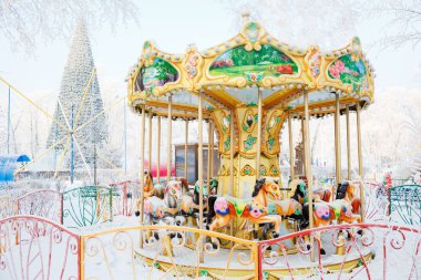 Atlı karıncaya geleneksel atları karla kaplı. Atlıkarınca büyük Noel ağacın arkasında.