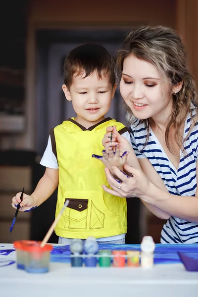 Entertaining kindertijd, een kleine jongen spelen met zijn moeder, tekent, schildert op de handpalmen. Het onderwijzen van kinderen tekenen, ontwikkeling van creatieve vermogens. Daglicht. — Stockfoto