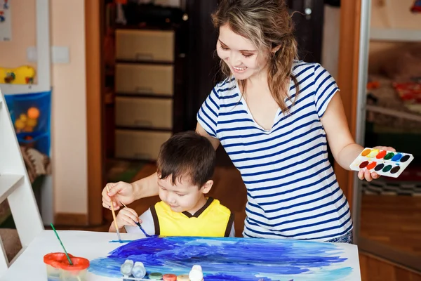 Vrolijke kindertijd, jongetje spelen met zijn moeder, tekent, schildert op de handpalmen. Het onderwijzen van kinderen tekenen, ontwikkeling van creatieve vermogens. Tekenen van een zee. — Stockfoto