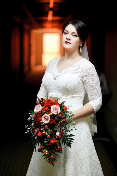 Brunette noiva com buquê de pé no corredor do hotel, luz do túnel . — Fotografia de Stock