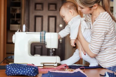 Küçük çocuk yeni bilgi öğrenir, dikiş makinesi annesi ile birlikte inceler. İş vasıl ev, ebeveynlik, ebeveyn ve çocuk, bakım, bebek bakıcısı.