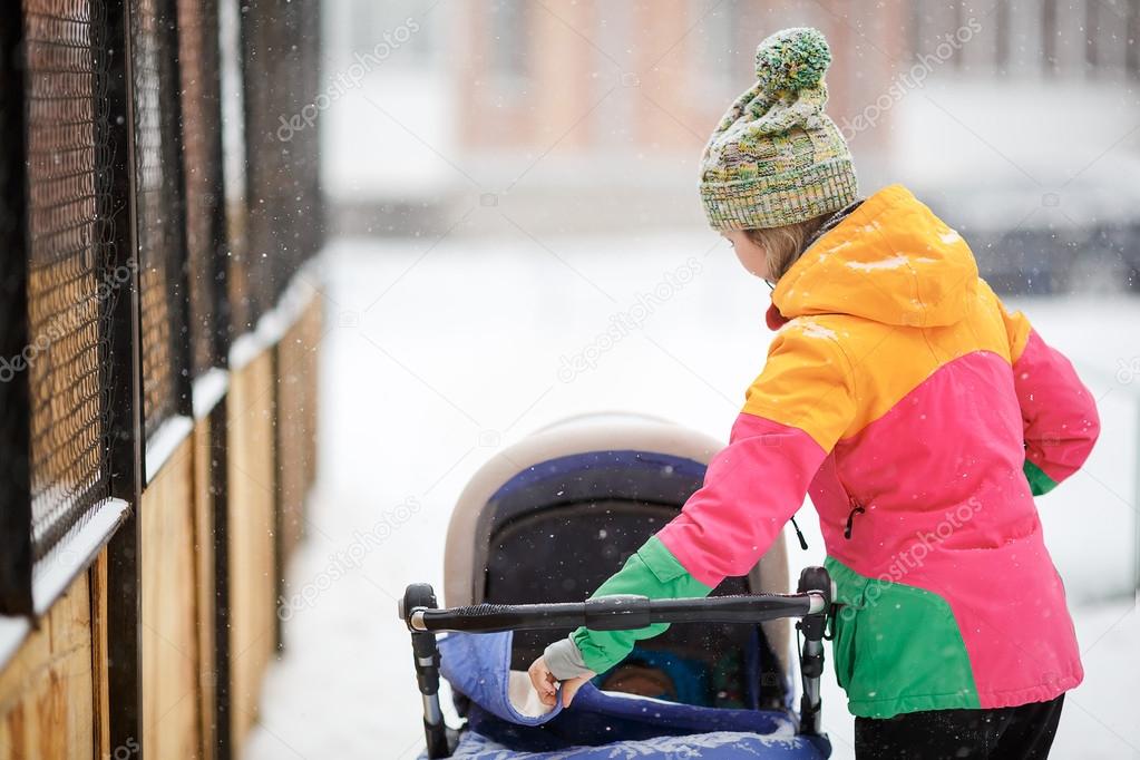 Mom and baby in stroller on walk, snowy winter Snowfall
