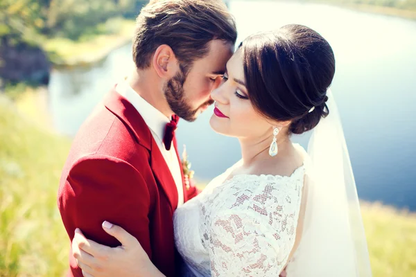 Bruid en bruidegom, mooie paar, knuffelen op de waterkant, foto shoot na de ceremonie van het huwelijk. Stijlvolle man met snor. — Stockfoto