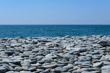 Mavi gökyüzüne karşı deniz kıyısındaki gri taşlar