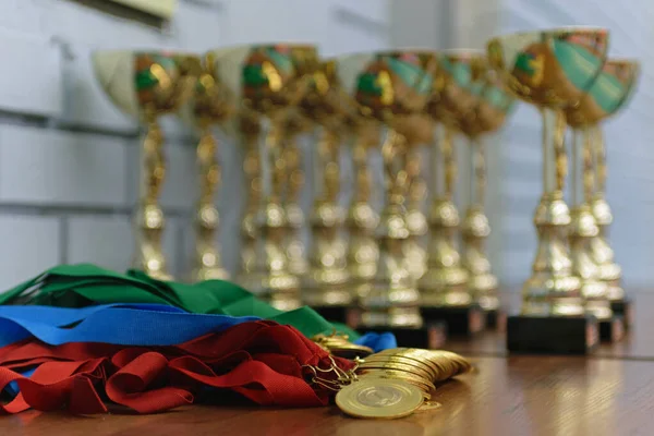 Medalhas Ouro Com Fitas Coloridas Copos Ouro Uma Mesa Madeira Fotografias De Stock Royalty-Free