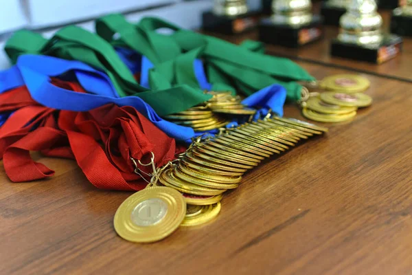 Medalhas Ouro Com Fitas Coloridas Copos Ouro Uma Mesa Madeira Imagens Royalty-Free