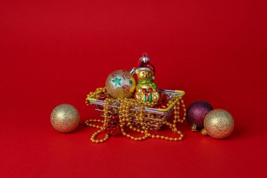 Kırmızı arka planda bir sepette Noel ağacı süslemeleri